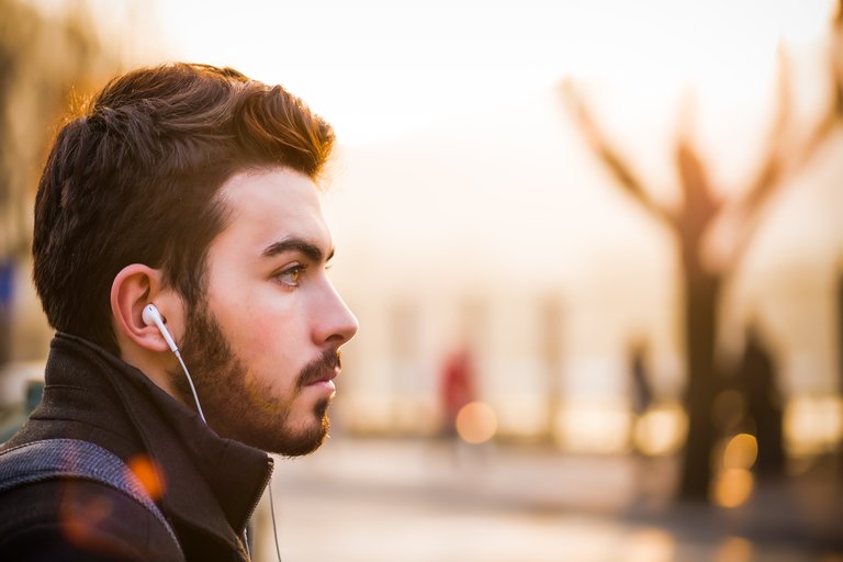 Young male listening to music using earbuds